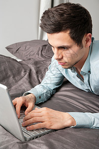 男人在床上用笔记本电脑图片