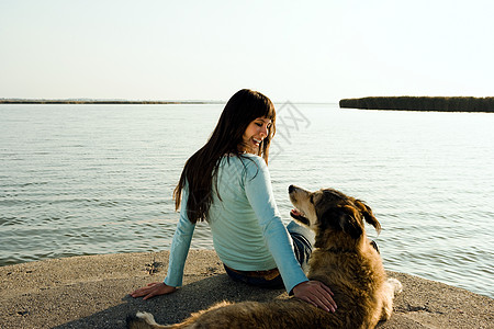 和狗一起坐在湖边的女人图片