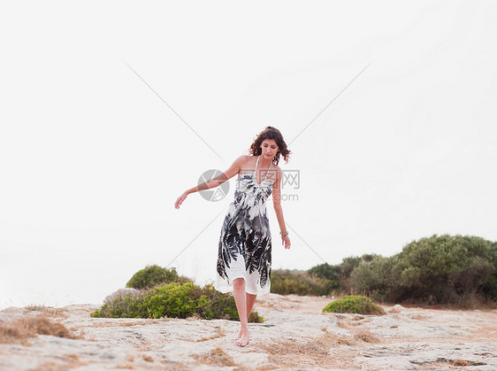 穿着衣服的女人在沙滩上行走图片