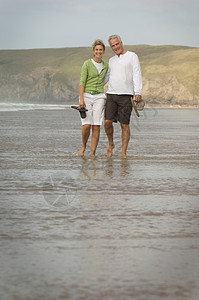 一对夫妇在海滩上手挽着手散步图片