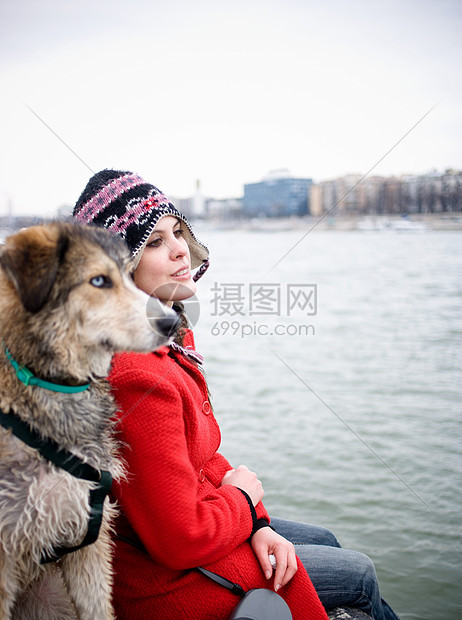 坐在河边带着狗的年轻女子图片