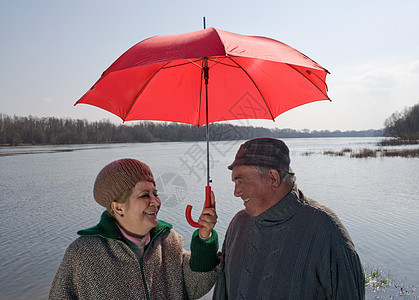 夫妇打着伞在江边合影图片