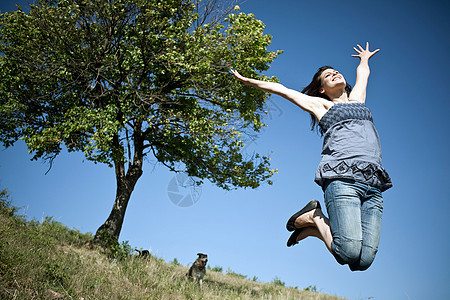 女人在树前面跳跃图片