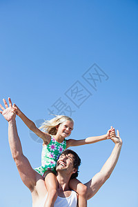 女儿坐在父亲肩膀上在沙滩上玩耍图片