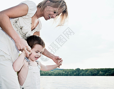 母亲扶着孩子在湖边图片