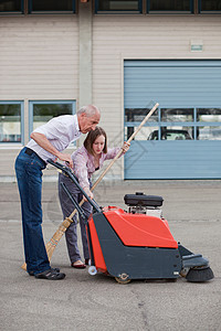 老人和少女用扫地机和扫帚清洁院子背景图片