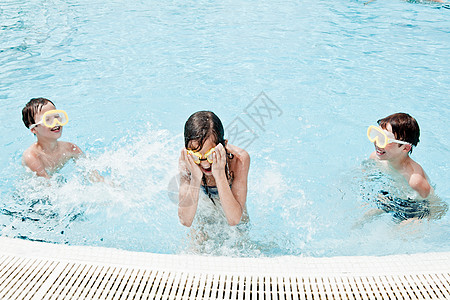 男孩在游泳池里向女孩泼水图片