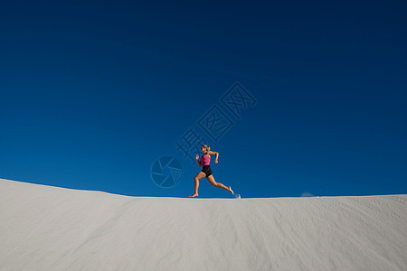 年轻女子在沙丘上奔跑图片