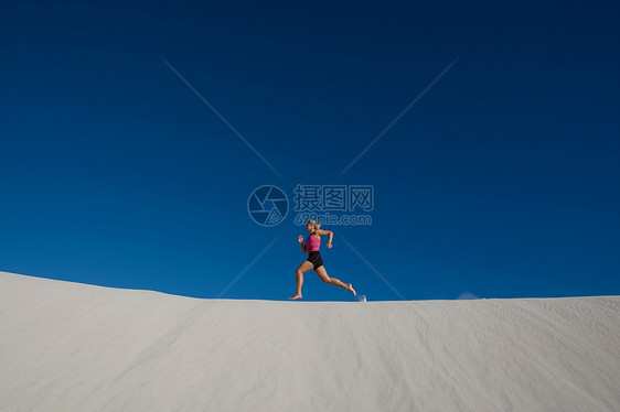 年轻女子在沙丘上奔跑图片