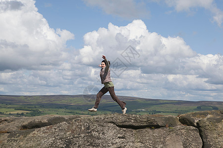 在岩石上跳跃的女人图片