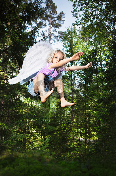 穿着翅膀在森林里跳跃的女孩图片