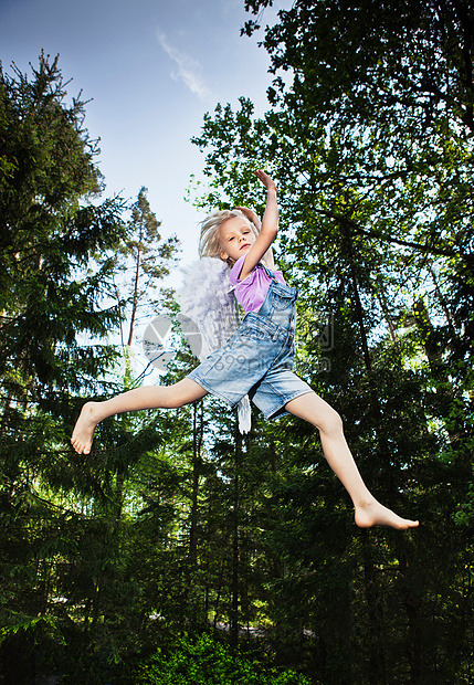 穿着翅膀在森林里跳跃的女孩图片