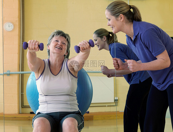 在健身房和教练一起锻炼的女人图片