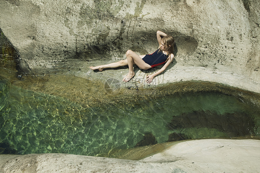 躺在小溪边的岩石上的女孩图片