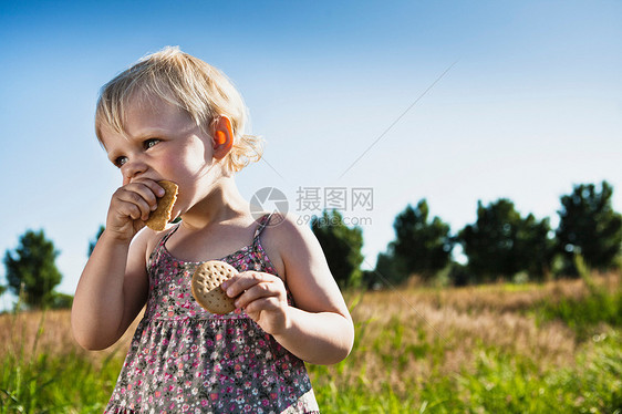 在户外吃饼干的小女孩图片
