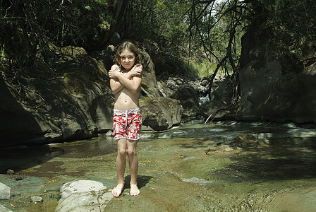 站在溪流中的岩石上的女孩图片