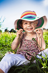 在草地上戴太阳帽的小女孩图片