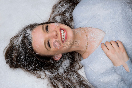 快乐的年轻女子躺在雪地里图片