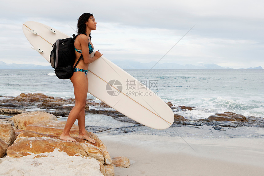 海滩上扛冲浪板的女人图片