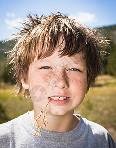 男孩边嚼着草边微笑图片