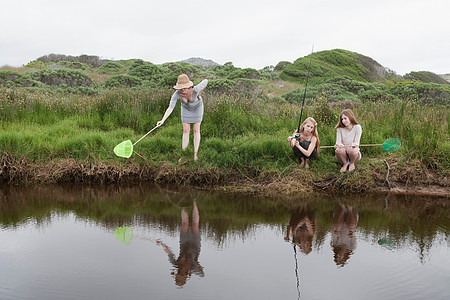 女孩们在小溪里用网捕鱼图片