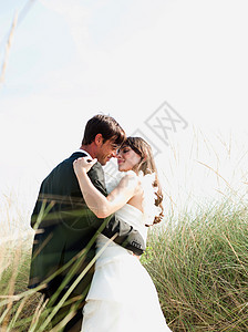 拥抱自然新郎新娘在海滩上跳舞背景