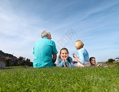 成熟的夫妇和孩子在草地上放松图片