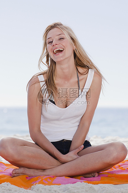 在海滩上坐在毛巾上的女人图片