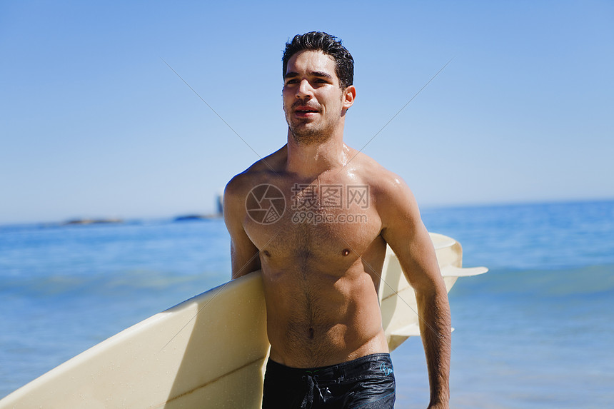 沙滩上扛冲浪板的人图片