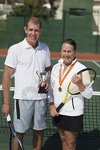 网球场上拿着奖杯的老年夫妇图片