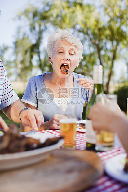 在野餐桌上吃饭的老女人图片