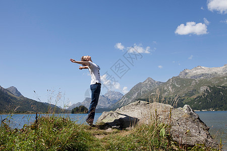 女人张开双臂站在湖边图片