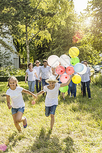 一群人在森林里奔跑和行走，男孩拿着一堆气球图片