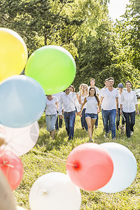一群人穿过森林，在前景中放着派对气球图片