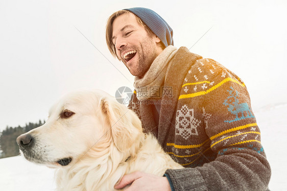 穿针织羊毛衫的男子在雪地狗图片