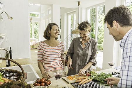 前期准备三个成年人在厨房准备新鲜蔬菜的照片背景