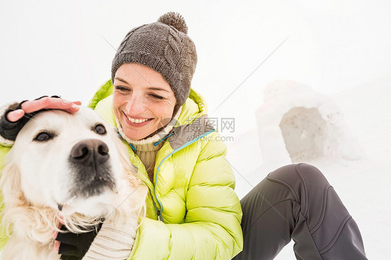 戴针织帽的女人拍狗的头图片