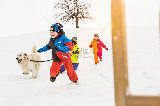 牵狗的孩子们在雪地里奔跑图片