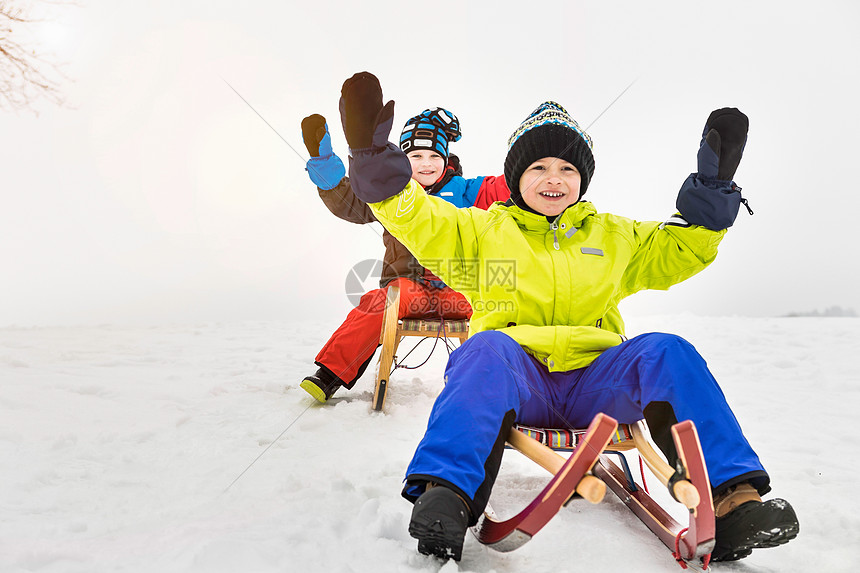 两个男孩在雪地里玩雪橇图片