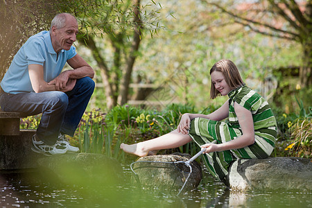 池塘边的老人和年轻女孩图片