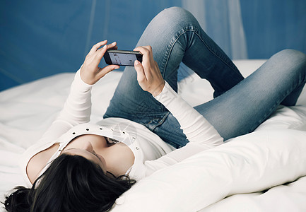 少女在床上玩手机图片