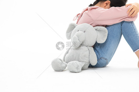 和玩具小象背靠背哭泣的小女孩图片