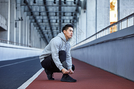 运动男青年系鞋带图片