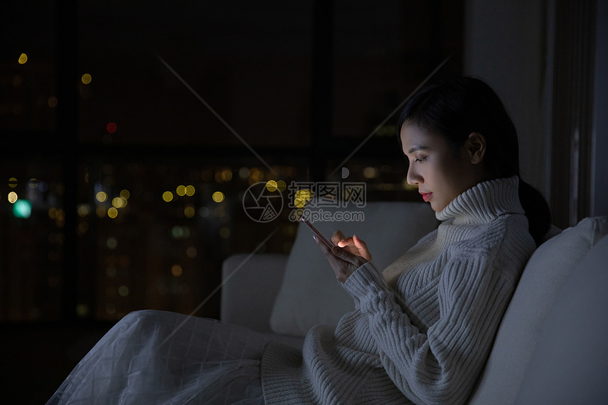 冬季青年女性夜晚玩手机图片