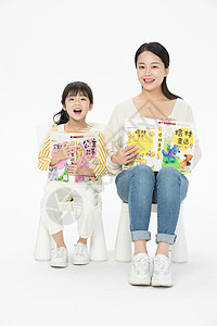 妈妈陪伴女儿坐在椅子上看童话故事书图片