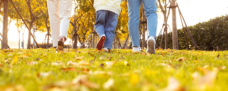 幸福一家爸爸妈妈带着女儿在公园草地奔跑背景
