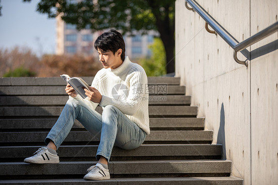 坐在楼梯上看书的青年男性图片