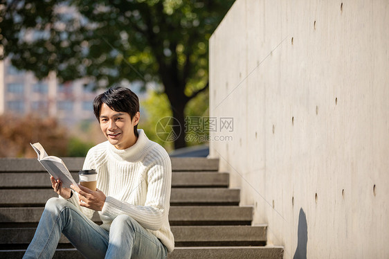 坐在楼梯上看书的青年男性图片