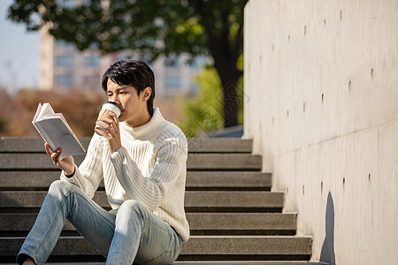 坐在楼梯上看书的青年男性图片