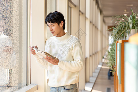 靠在窗前阅读的男性图片